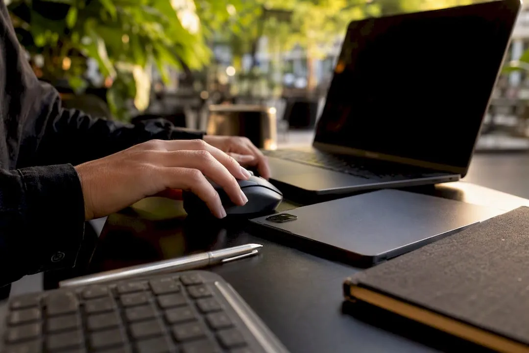 Hands adjusting mouse beside tablet on desk